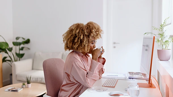 a woman sitting at a desk drinking from a cup