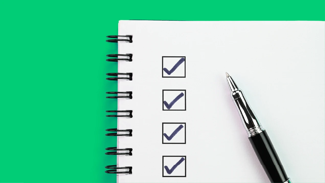 a pen next to a spiral notebook with check boxes