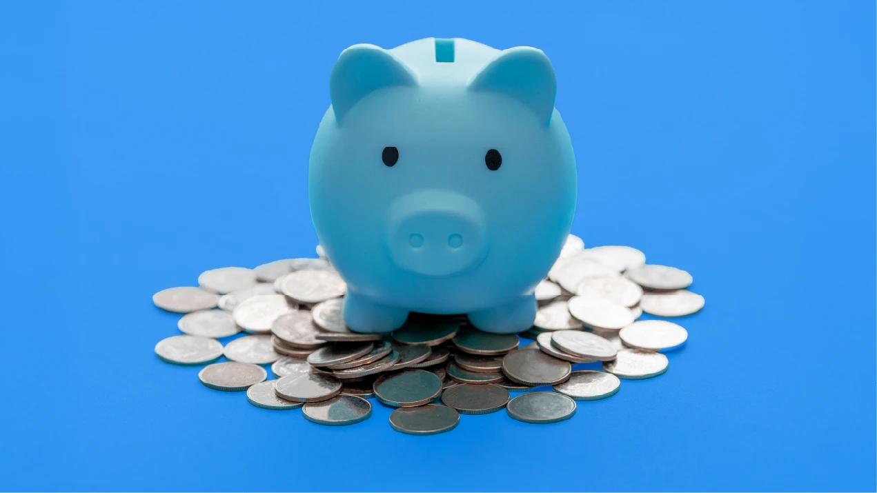 a blue piggy bank on a pile of coins