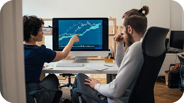 a group of people sitting at a desk looking at a computer screen